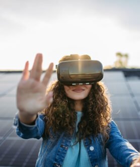 Young woman with virtual goggles on a roof with solar panels.